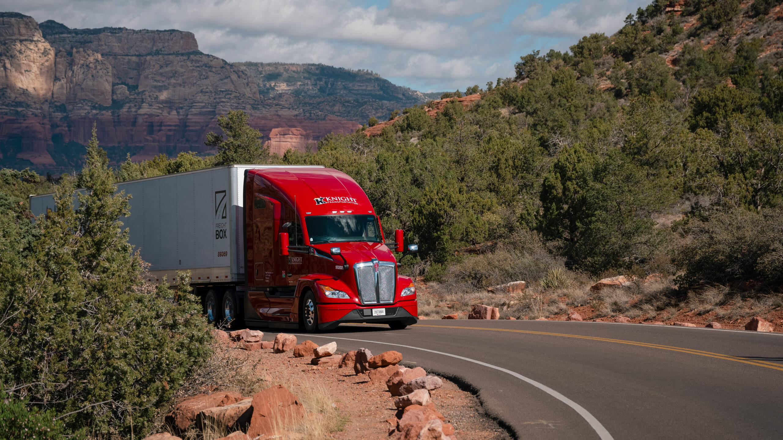 A knight Transportation truck drives on a scenic road.